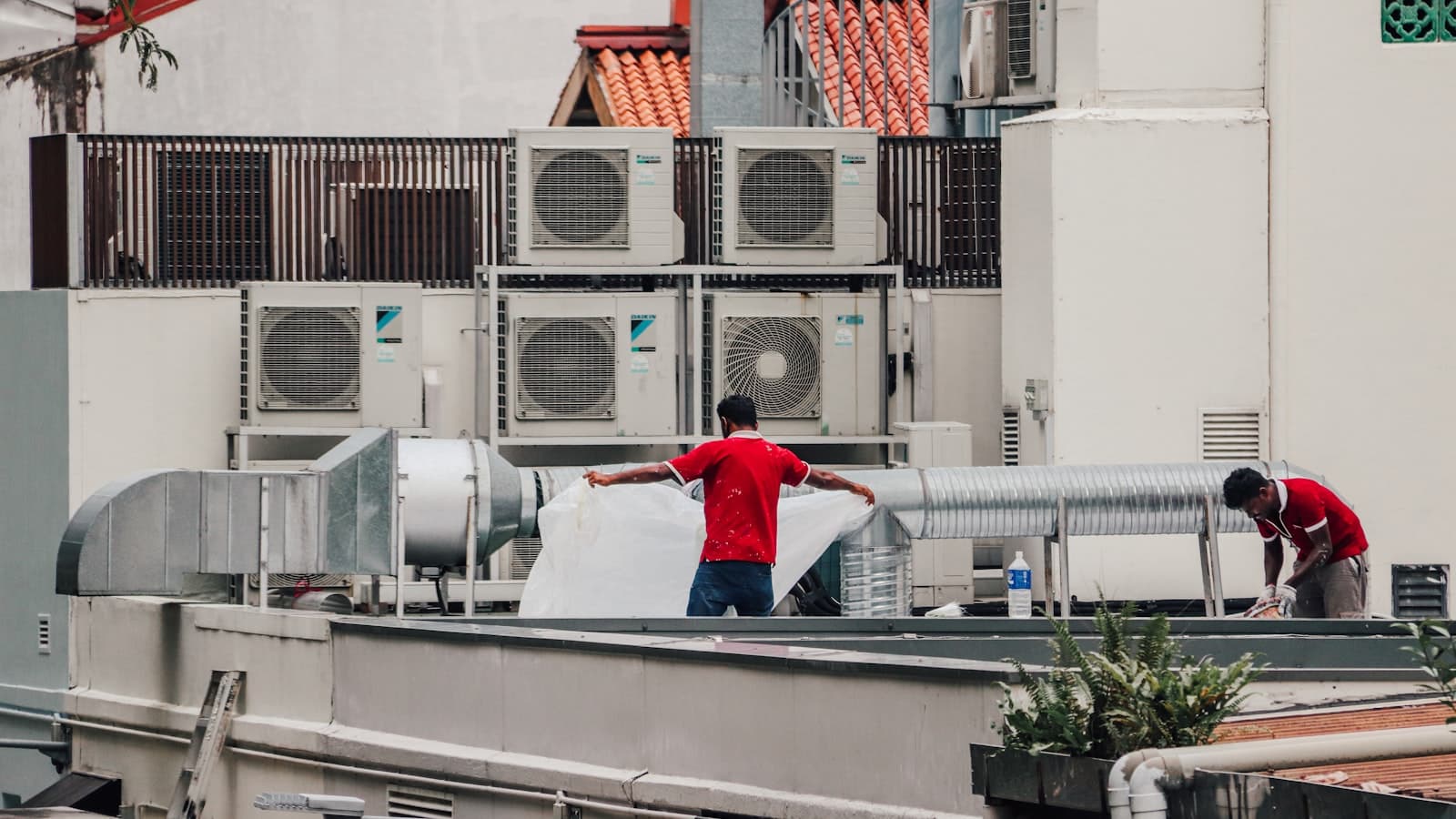 Technicians servicing condenser units on a rooftop